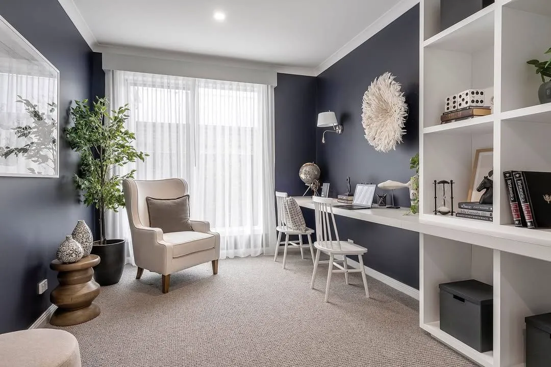 Home office with deep navy painted walls and white shelving